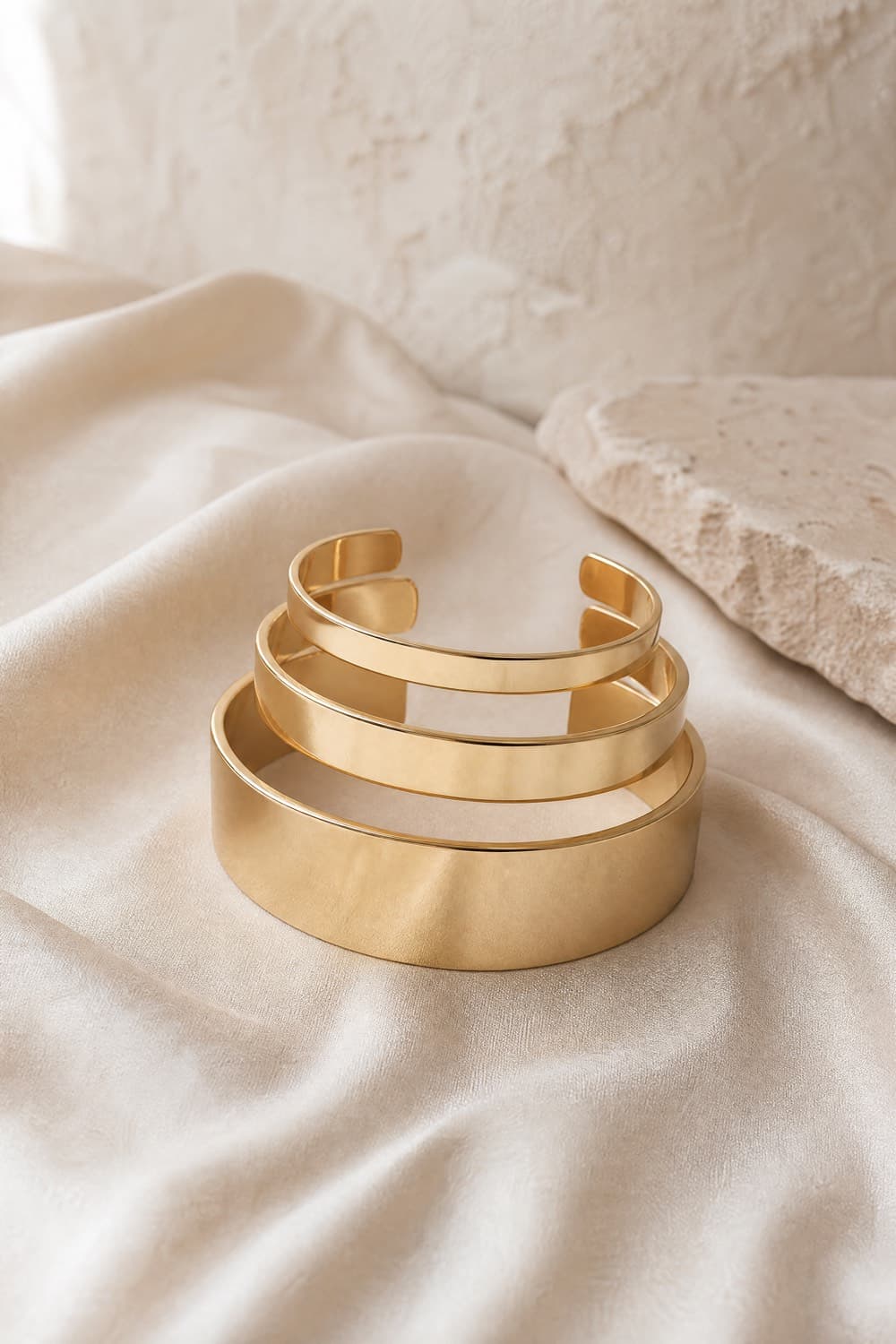Three open gold-tone cuffs in graduated widths stacked together
