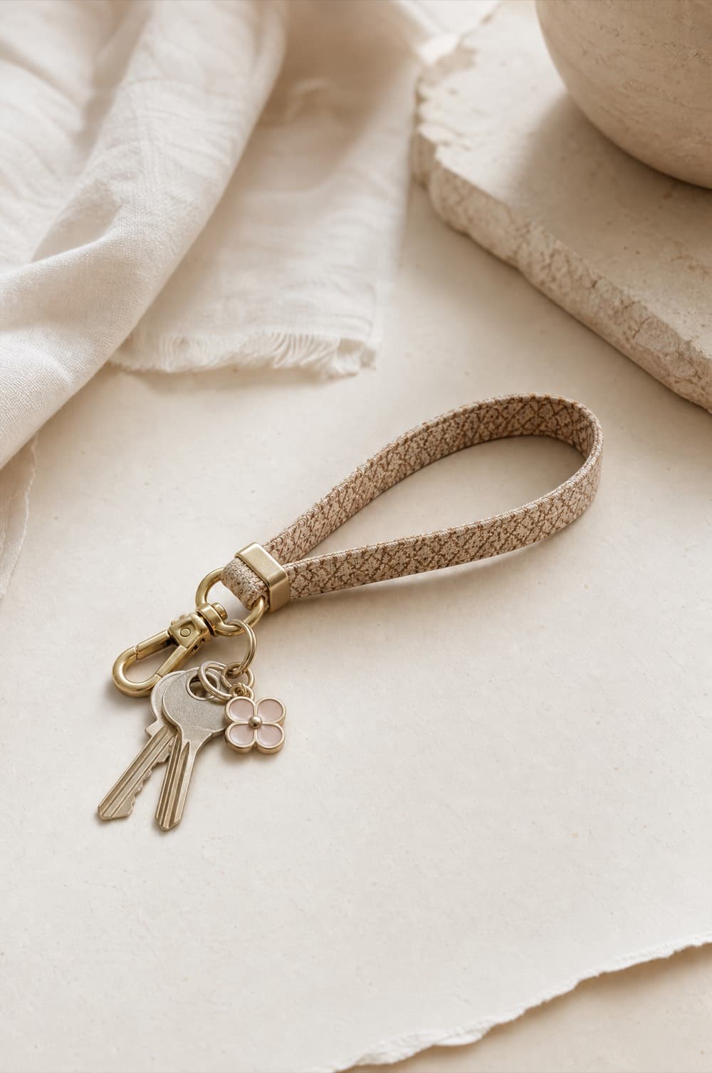 Tan wristlet key loop with a gold-tone swivel clip and small charm