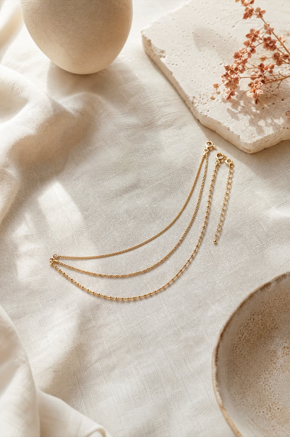 Three fine gold-tone chains at different lengths laid in parallel