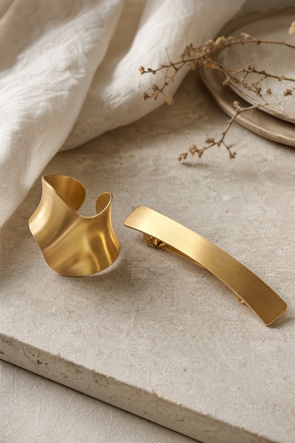 Gold-tone hair cuff and long flat barrette on a neutral surface