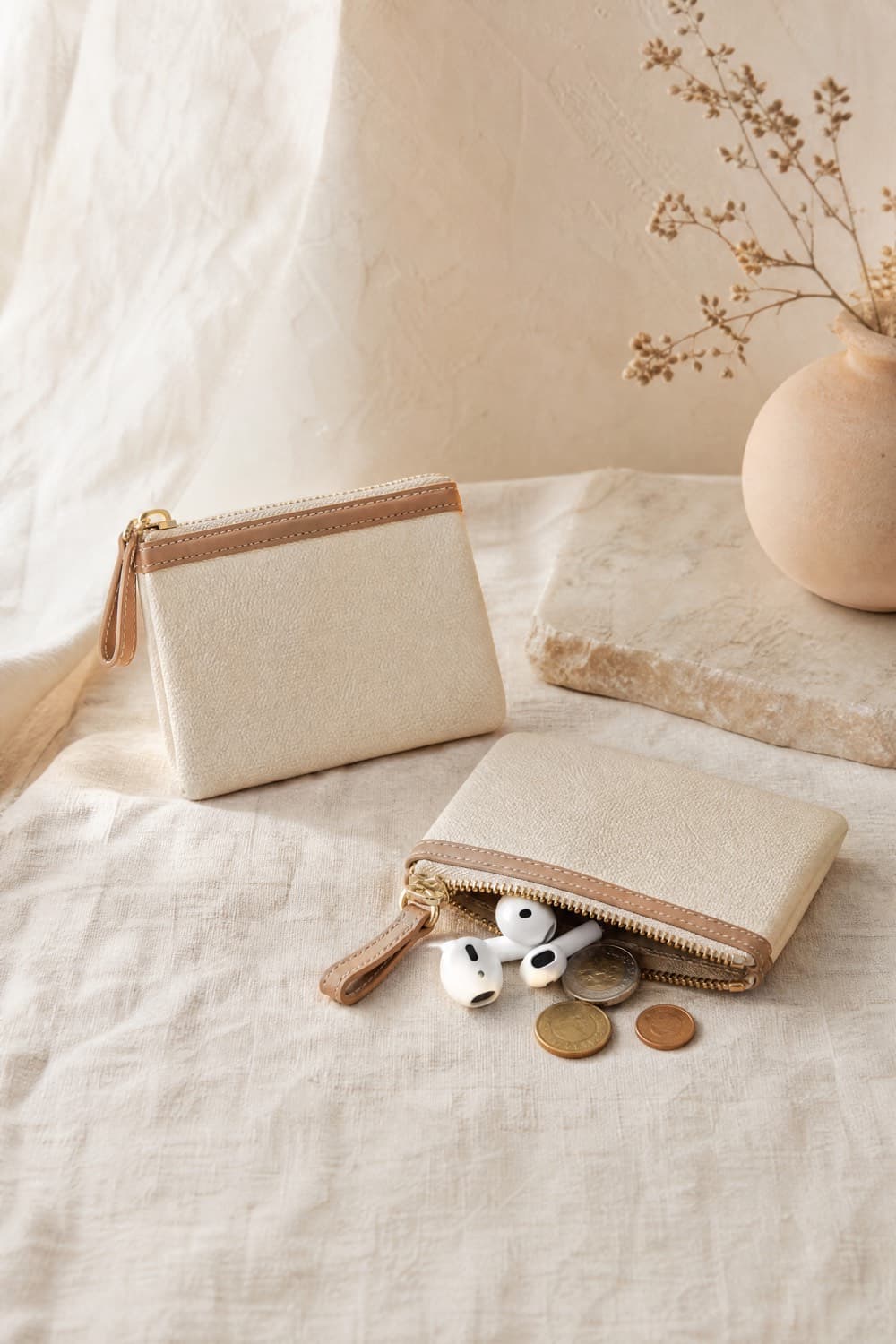 Two small zip pouches in cream and tan, one open