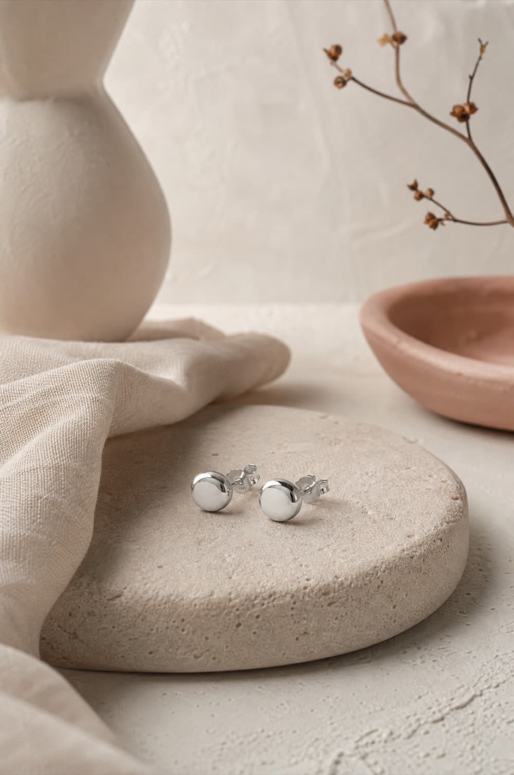 A single pair of minimal sterling silver stud earrings on grey stone